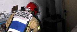 Strażak sprawdza piec znajdujący się w pomieszczeniu, w którym doszło do wybuchu