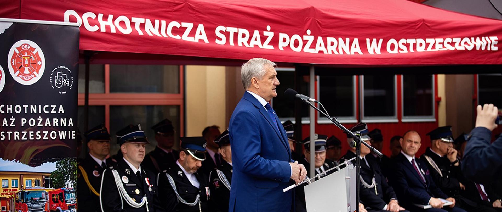 Sekretarz stanu MSWiA w trakcie przemowy. Na drugim planie zaproszeni goście.