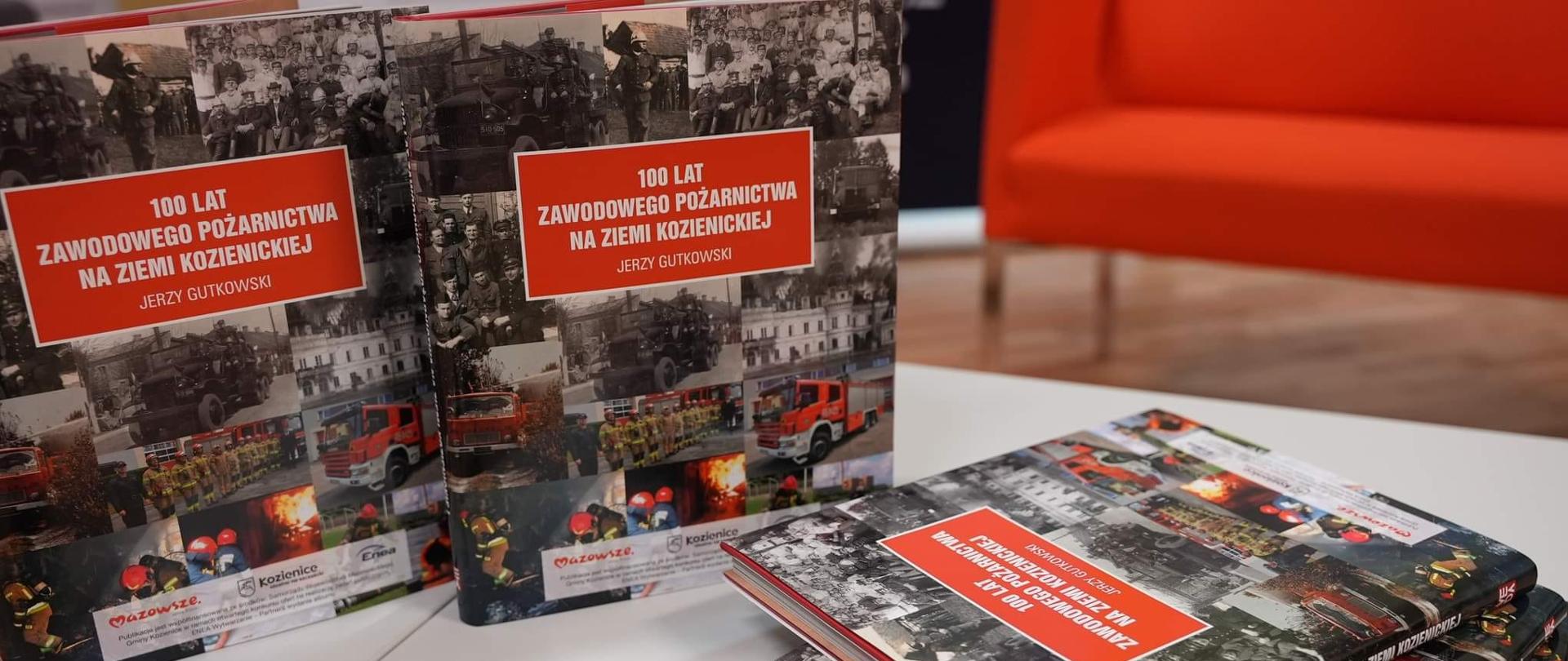 książki pt. "100 lat zawodowego pożarnictwa na Ziemi Kozienickiej" rozłożone na stoliku