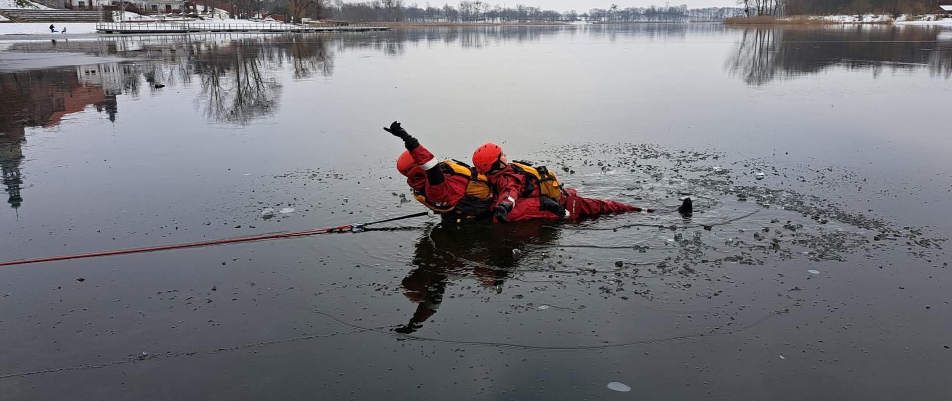 Ćwiczenia z ratownictwa lodowego na jeziorze chełmżyńskim. Podjęcie osoby poszkodowanej z wody przez ratownika. 