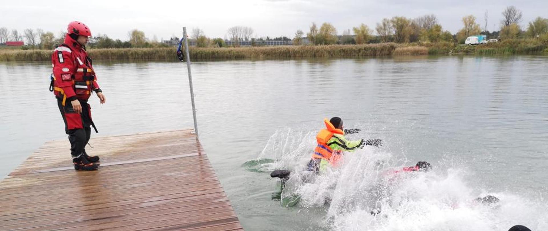 Na zdjęciu strażacy podczas skoku do wody z pomostu