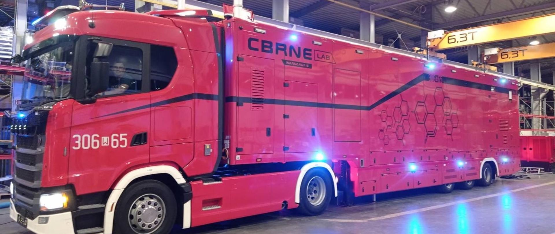 Samochód do działań CBRNE dla PSP stoi w hali , za kierownicą siedzi kierowca - strażak