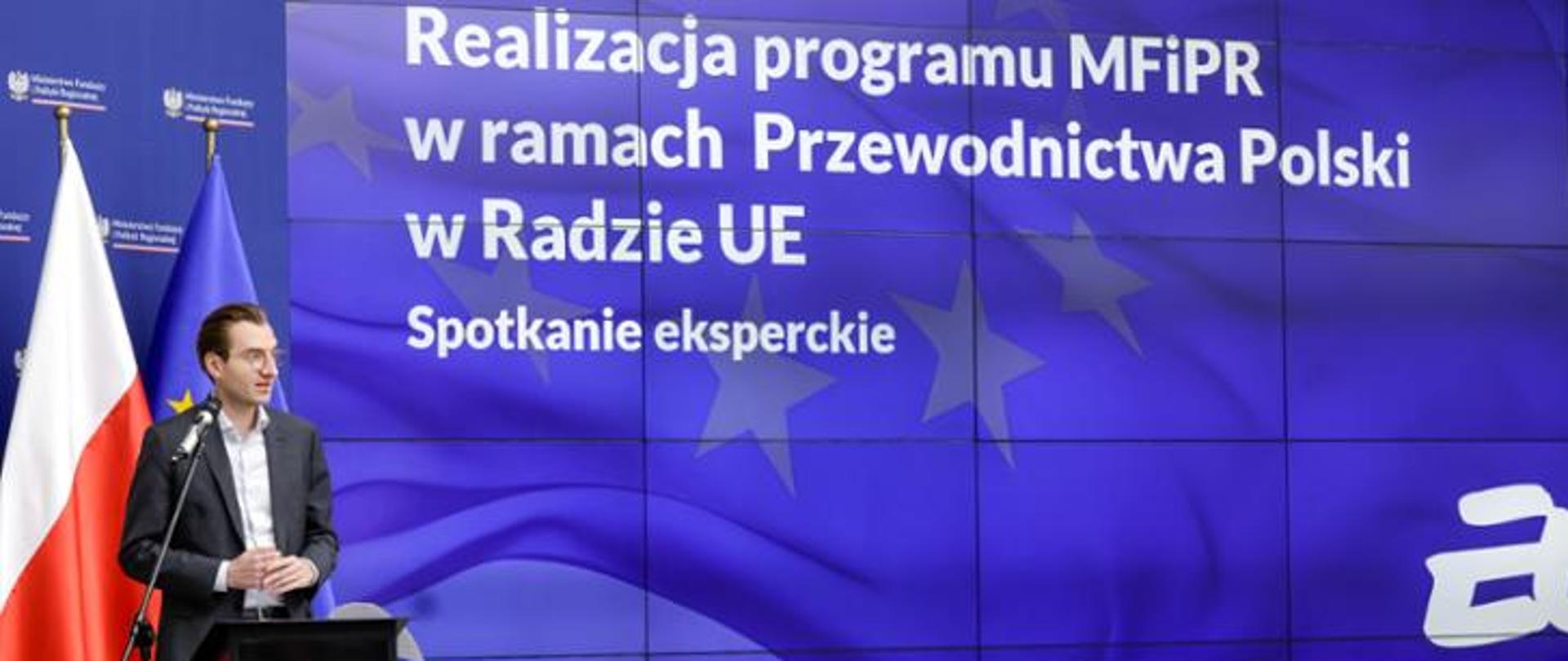 In the photo, Deputy Minister Jan Szyszko stands on the stage, in the background there is a poster with the title of the conference