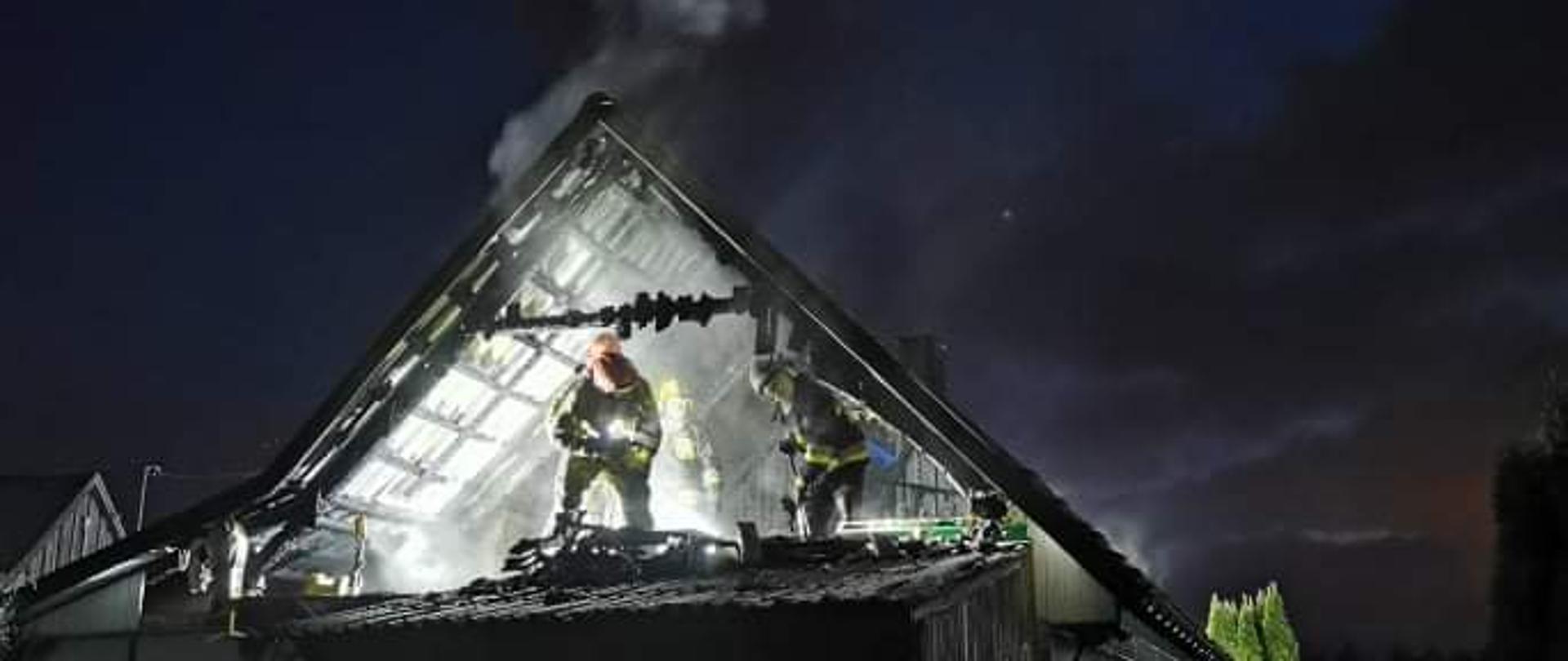 Fotografia przedstawiająca działa gaśnicze prowadzone przez strażaków podczas pożaru poddasza w domu jednorodzinnym w miejscowości Hucisko.