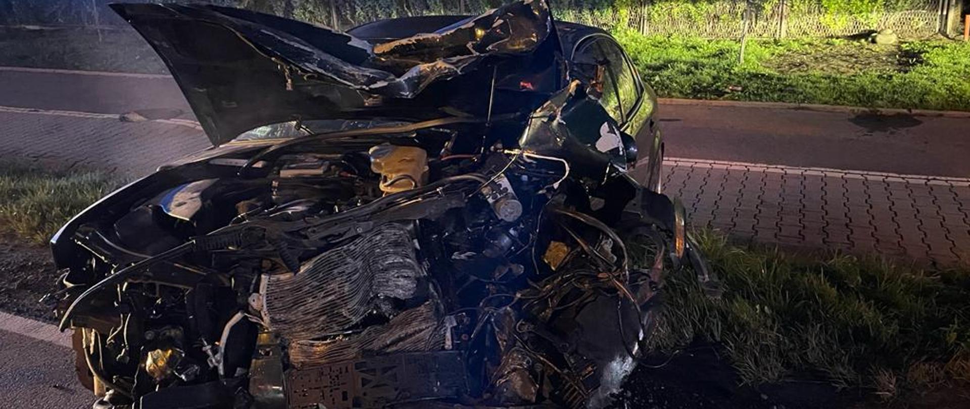 Rozbity przód samochodu osobowego na poboczu.