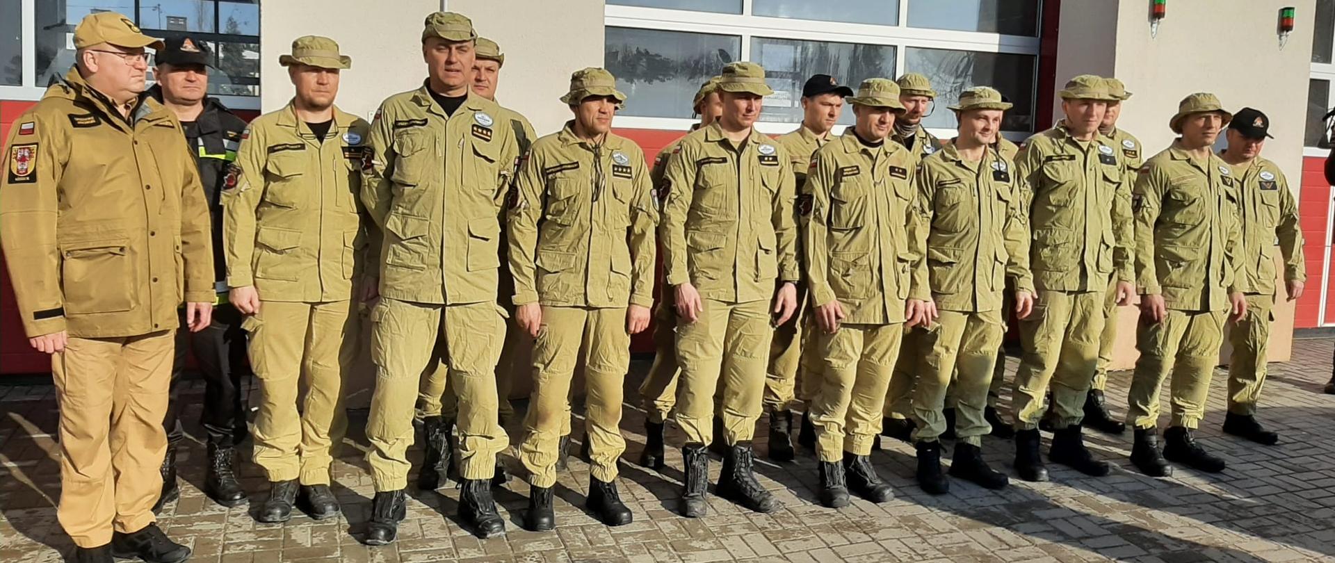 Strażacy z SGPR "Łódź" wraz z łódzkim komendantem wojewódzkim psp oraz komendantem miejskim psp stojący w dwóch rzędach przed bramami jednostki ratowniczo-gaśniczej nr 9 