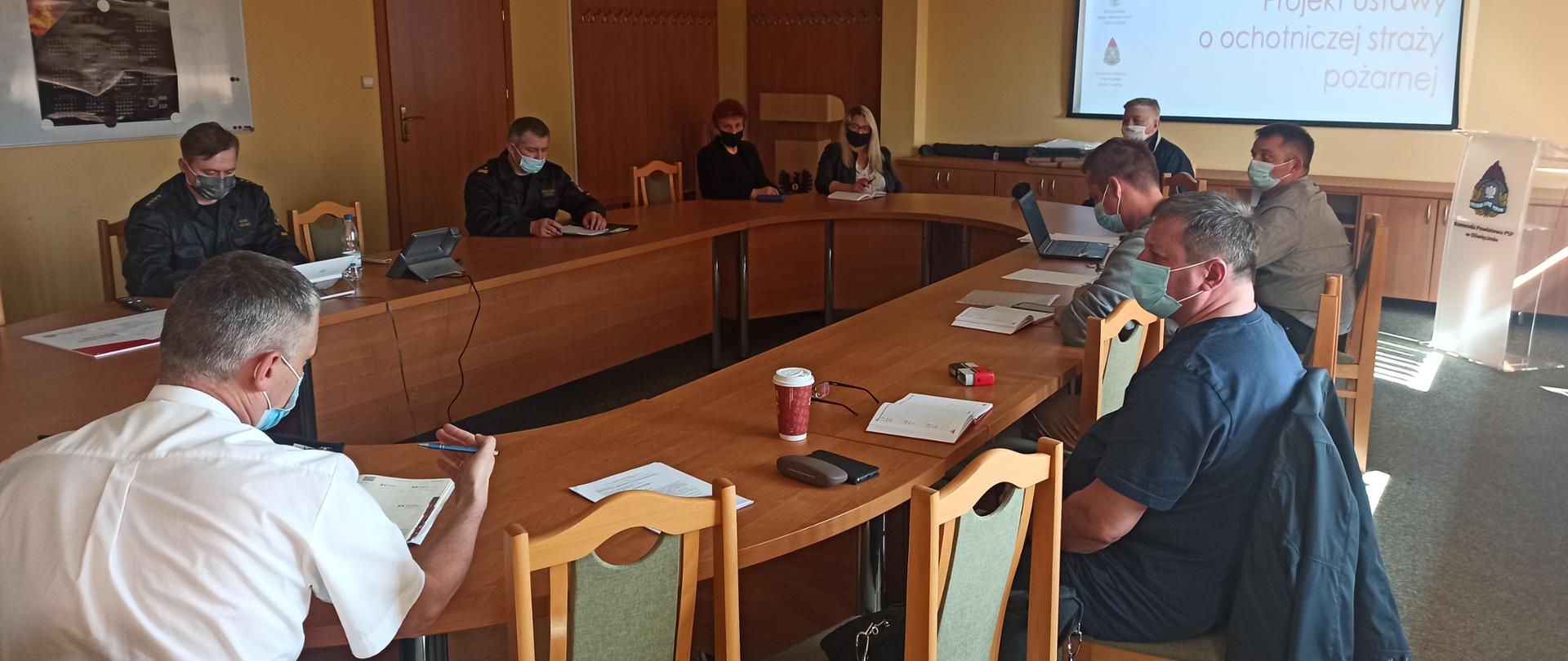 przy stole siedzą funkcjonariusze oraz druhowie w maseczkach 