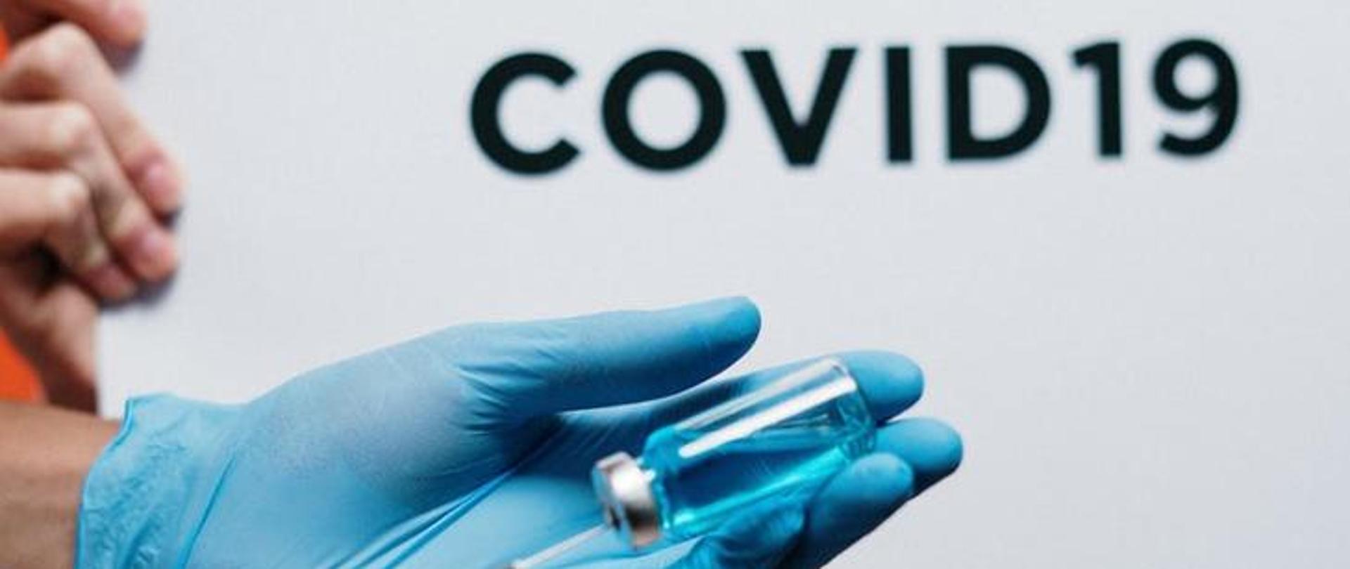 Dłoń w błękitnej rękawiczce jednorazowej.