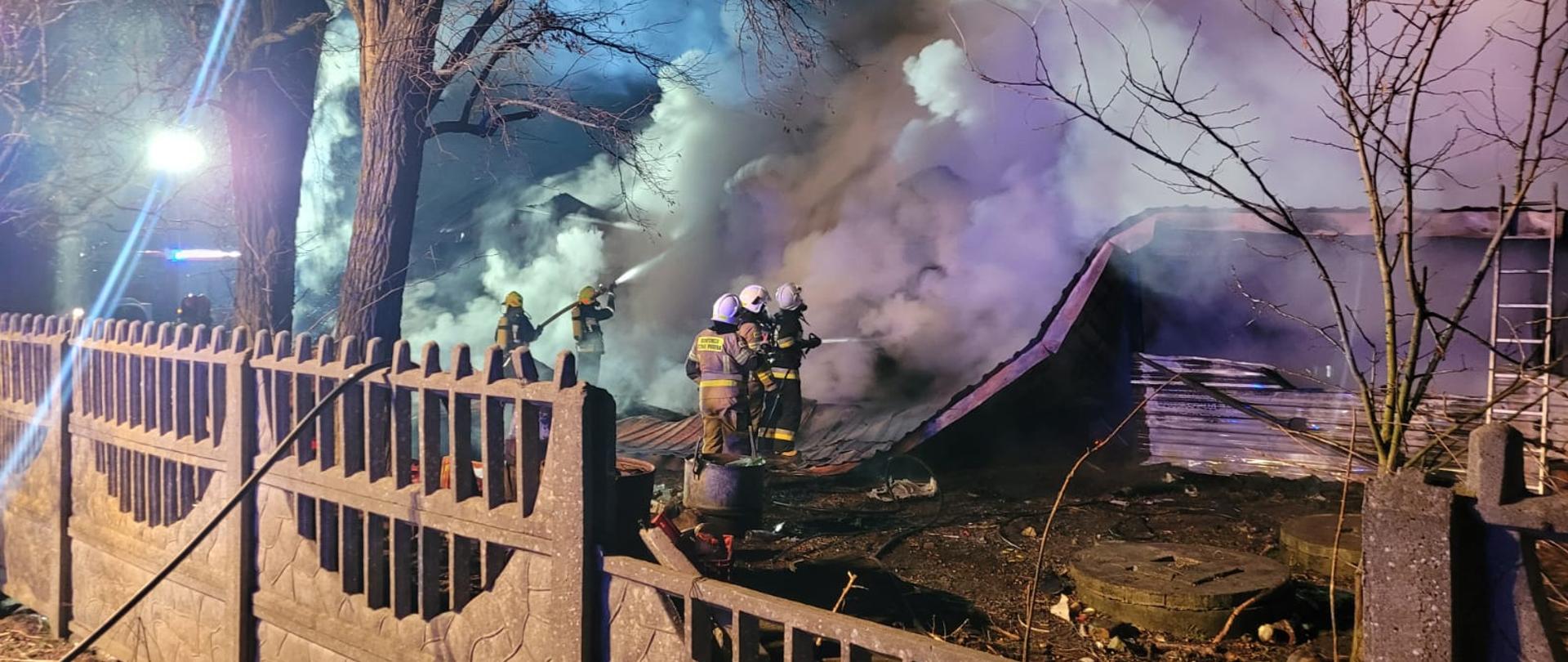 Na zdjęciu strażacy podają prądy gaśnicze na budynek objęty pożarem