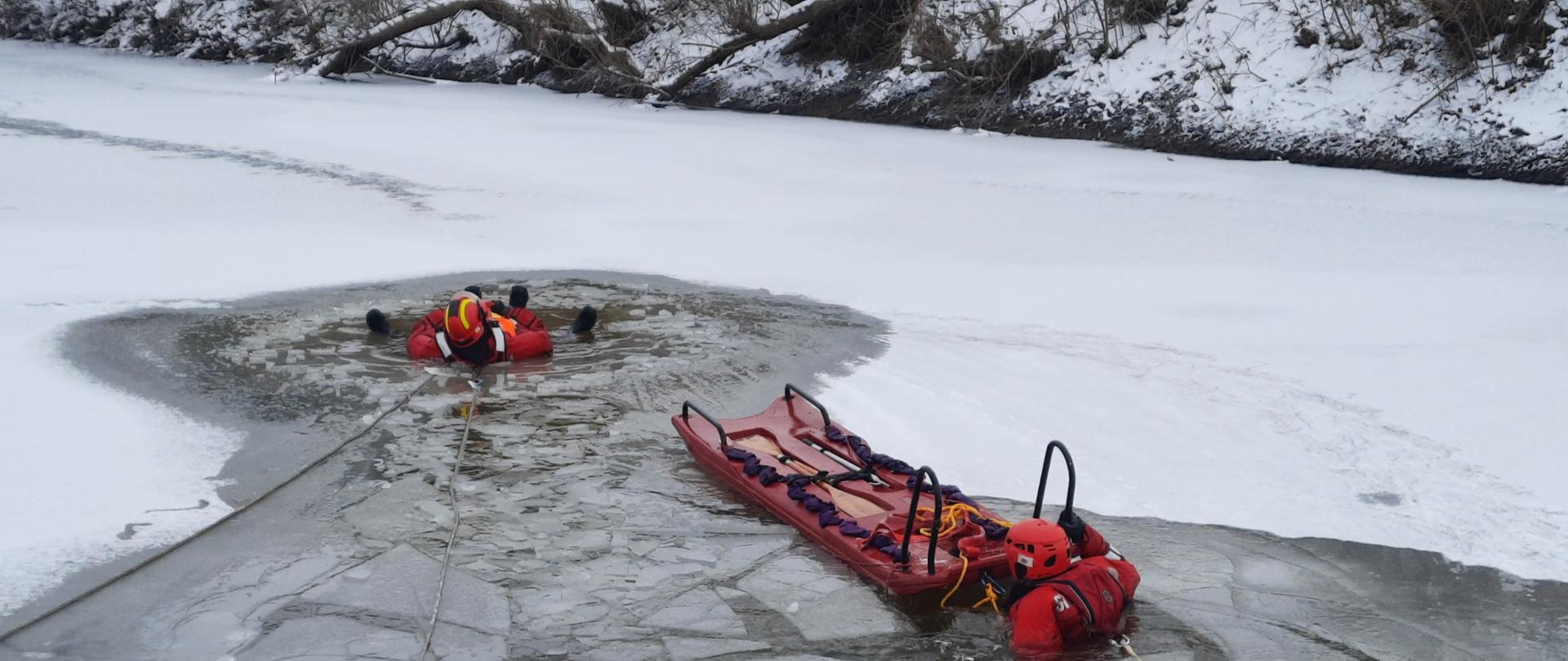 Strażacy przy użyciu posiadanego sprzętu z zakresu ratownictwa lodowego ćwiczą wydobywanie osób znajdujących w wodzie, pod załamanym lodem. 