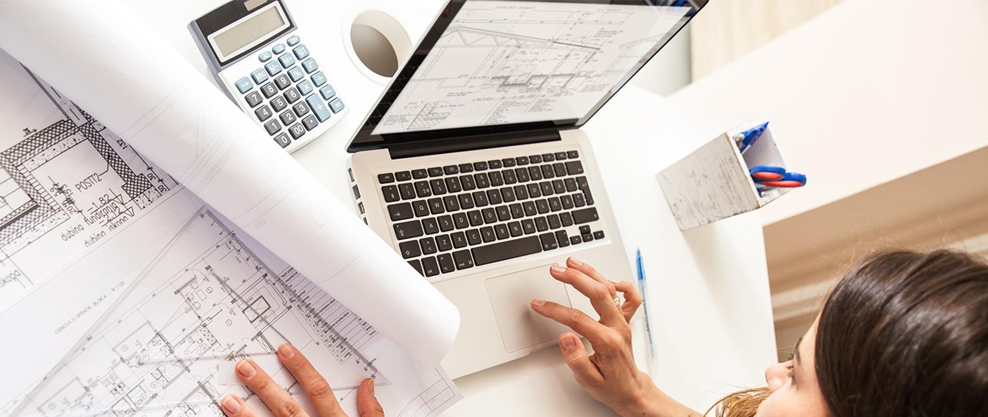cyfryzacja procesu budowlanego na zdjęciu osoba wprowadzająca dane z projektów budowlanych do komputera