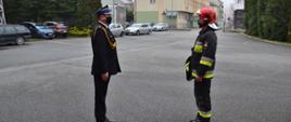 Dowódca zmiany umundurowany w ubranie specjalne składa meldunek D-cy JRG. Dowódca JRG Ubrany w mundur wyjściowy