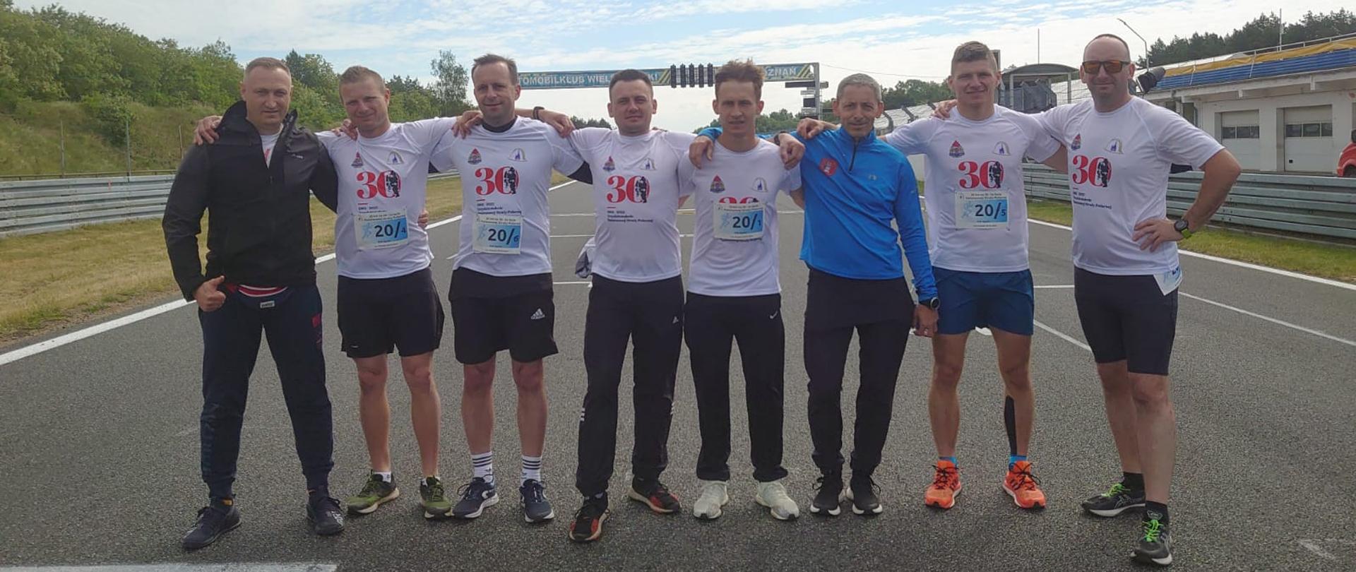 Funkcjonariusze PSP z województwa opolskiego wraz z kierownikiem drużyny na "Torze Poznań" we wspólnym zdjęciu w strojach sportowych.