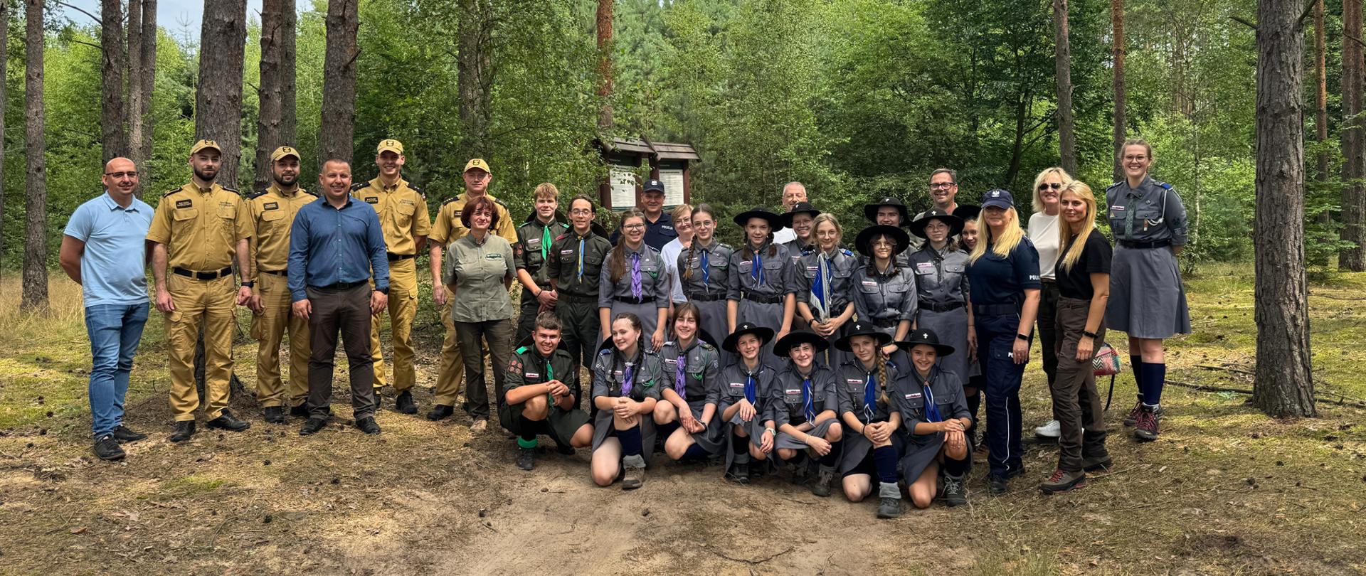 Zdjęcie przedstawia grupę harcerzy wraz z przedstawicielami obecnymi na wizytacji obozów harcerskich