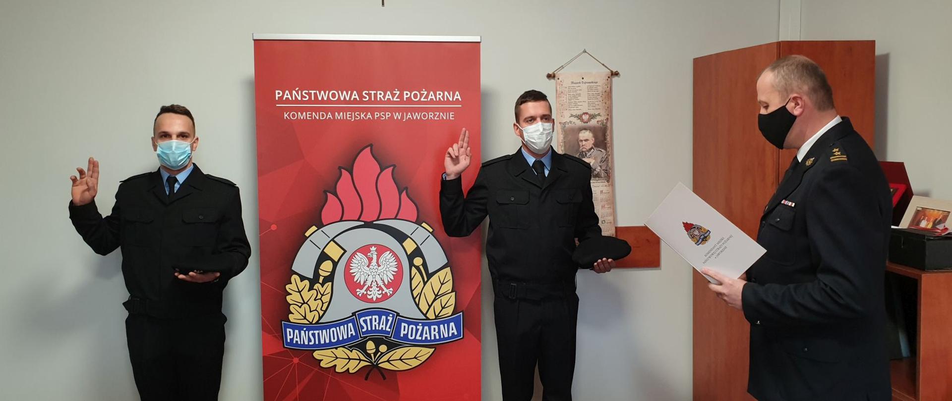 Zdjęcie przedstawia bryg. mgr inż. Paweł Żaba odbierającego ślubowanie od str. Damiana Węgrzyna oraz str. Armina Zycha w pomieszczeniu biurowym KM PSP w Jaworznie.