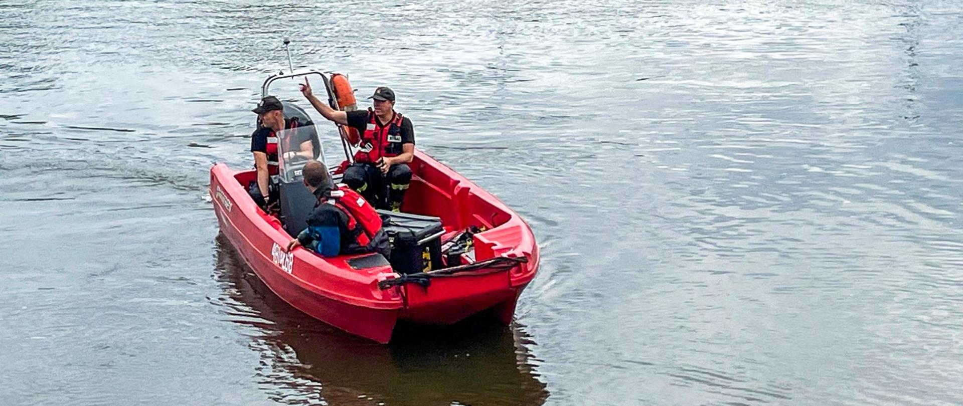 Na zdjęciu trzech strażaków na łodzi strażackiej na rzece
