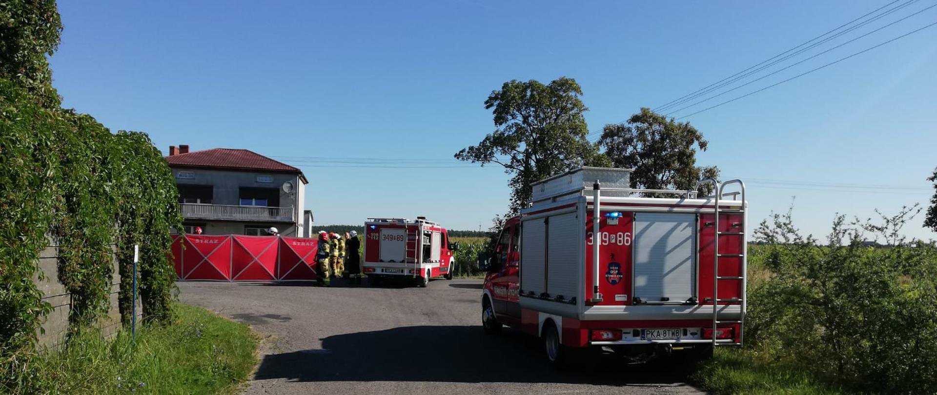 Na zdjęciu widać ratowników. Zdjęcie w ciągu dnia. Słonecznie. Brak zachmurzenia. Zdjęcie wykonane podczas działań ratowniczo-gaśniczych. Widać pola uprawne.