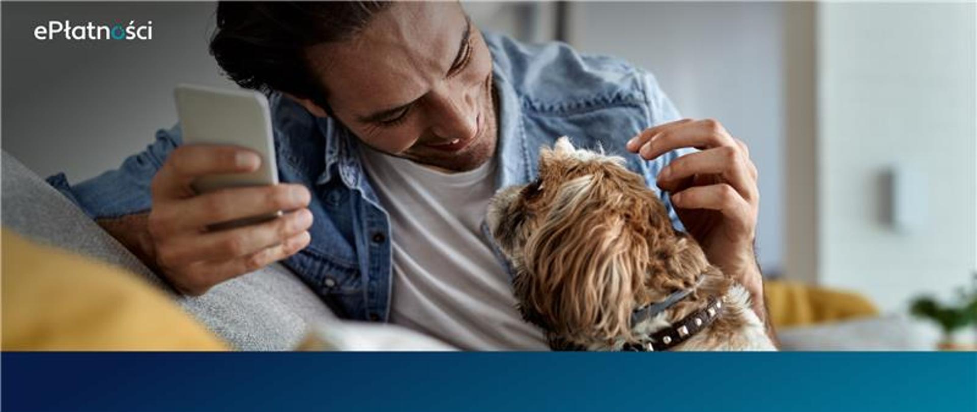 W lewym górnym rogu logo ePłatności. Na zdjęciu mężczyzna głaszczący psa, w prawej ręce trzyma telefon