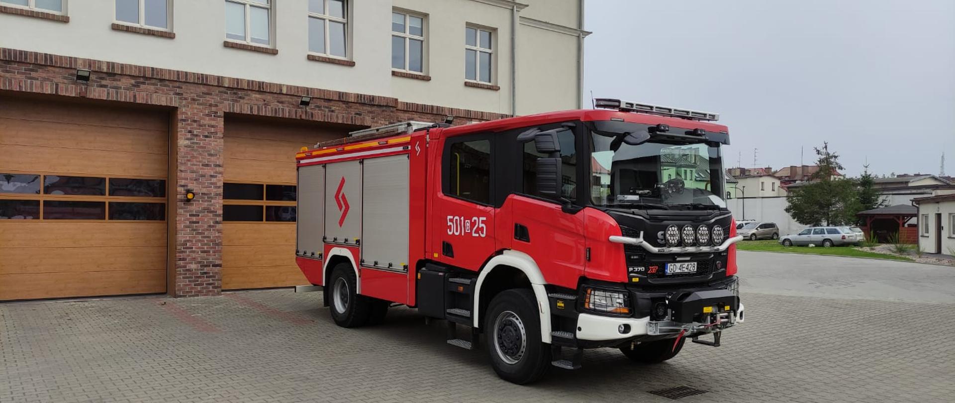 Na zdjęciu widać samochód marki scania na tle budynku jednostki ratowniczo- gaśniczej w Pucku