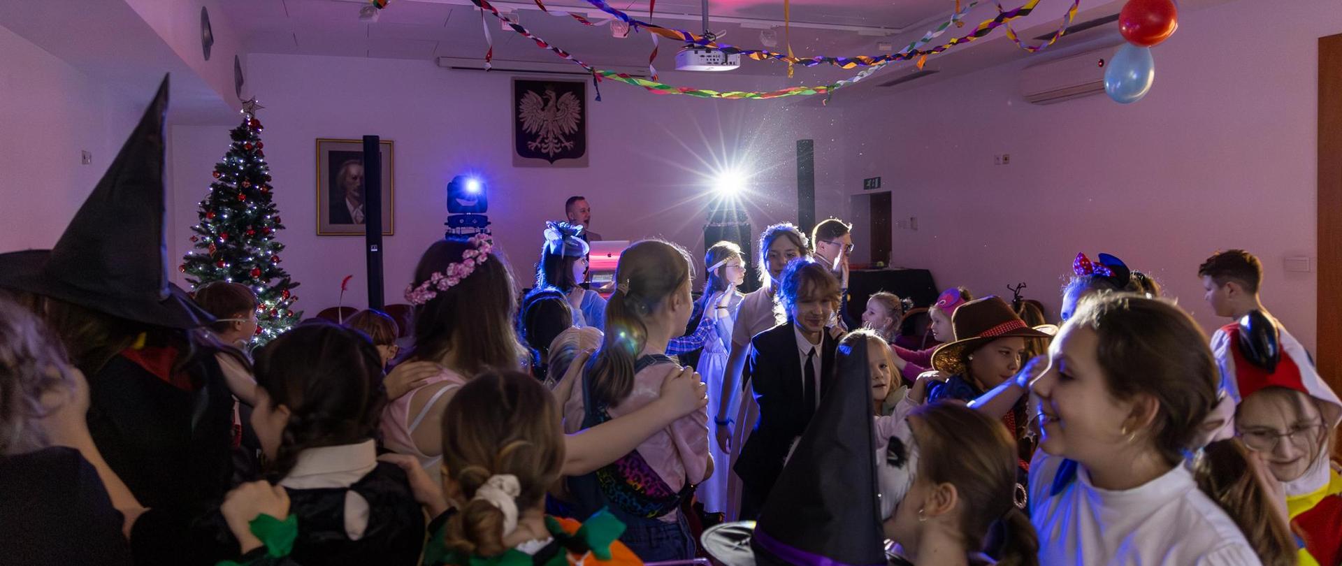 Bal karnawałowy 2024. Uczniowie i nauczyciele w przebraniach karnawałowych bawiący się na auli PSM w Głubczycach. Prowadzenie balu - Paweł Ganczarski.