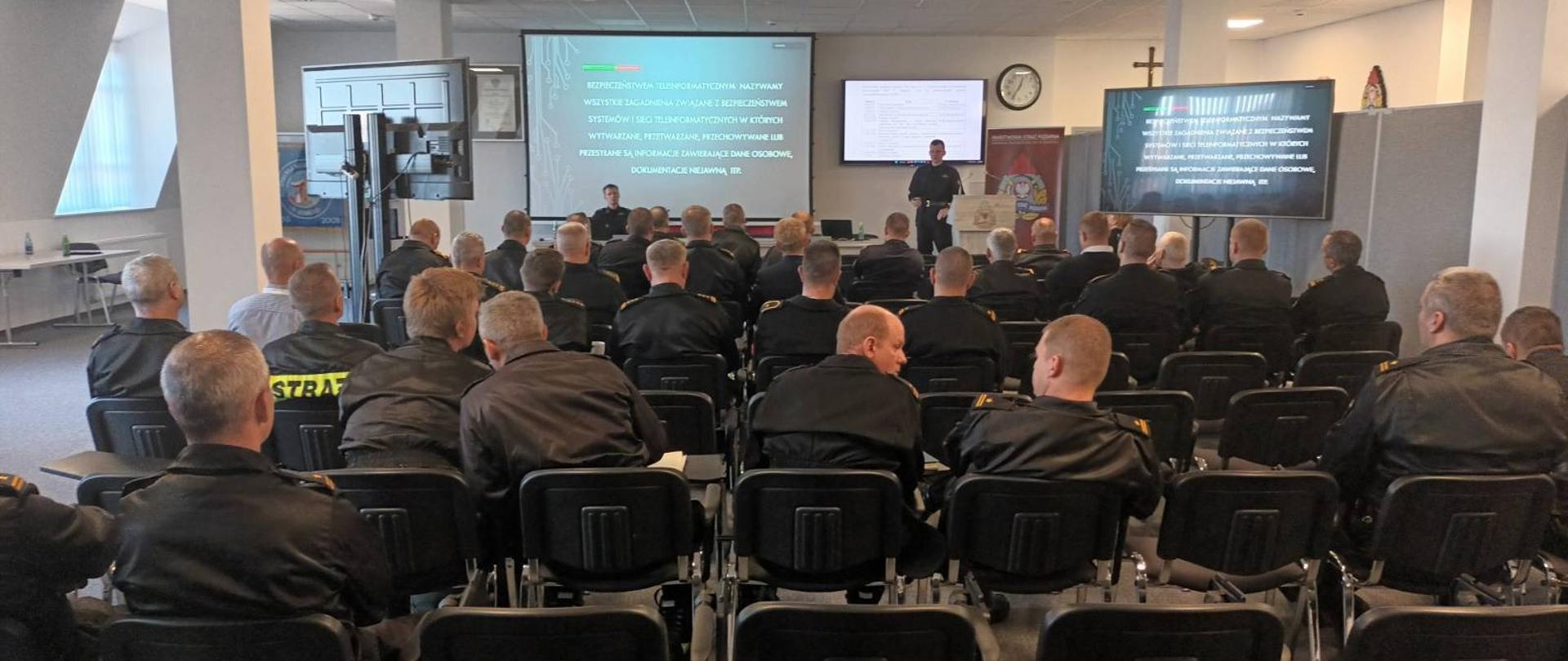 Na zdjęciu widzimy strażaków słuchających wykładu podczas szkolenia