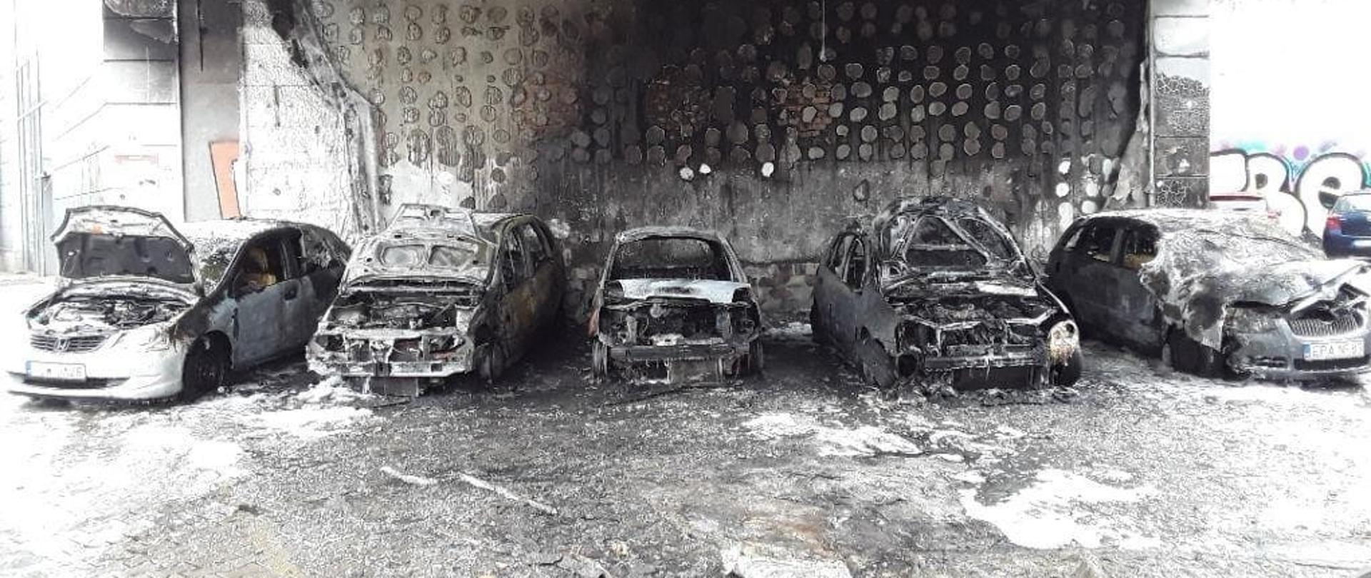 Pięć spalonych samochodów osobowych zaparkowanych obok siebie.