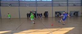 Strażacy Państwowej Straży Pożarnej w strojach sportowych na hali w Kluczborku grają w piłkę podczas mistrzostw w futsalu.