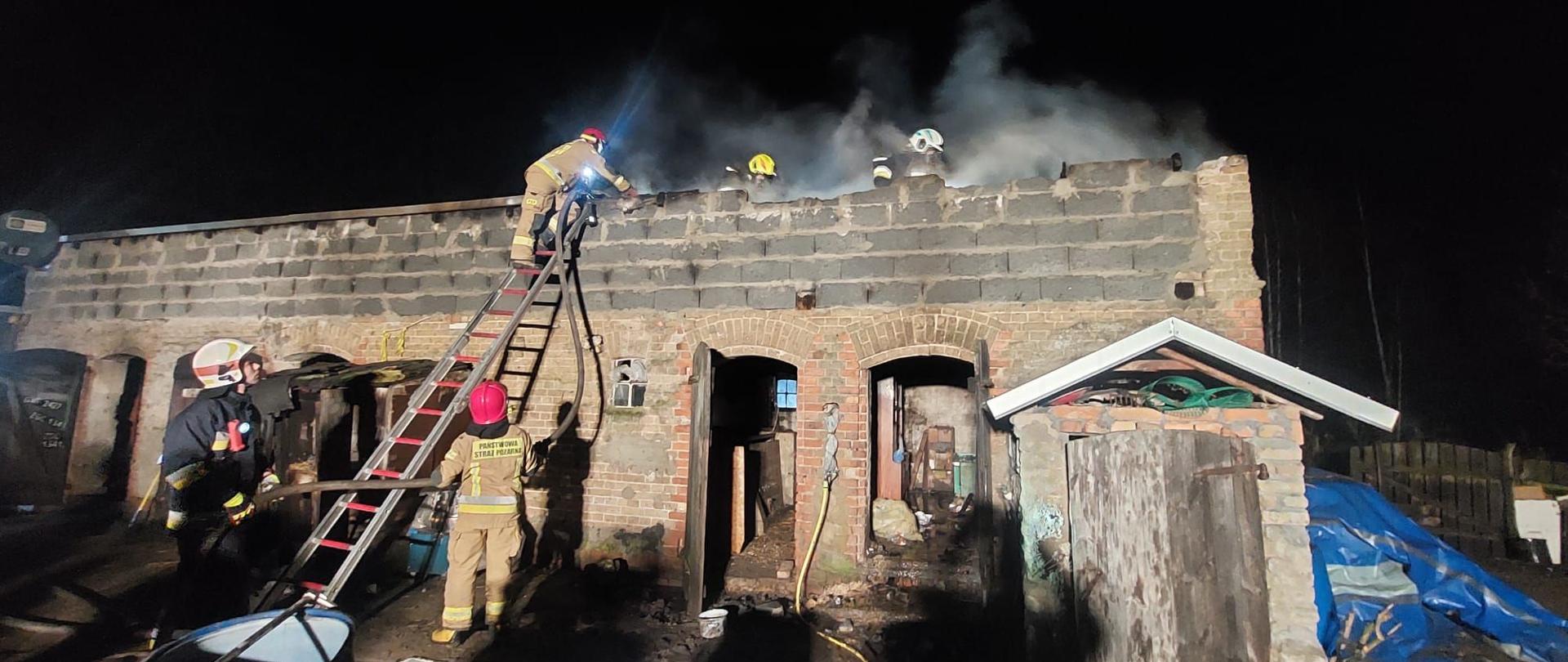 Strażacy prowadzący działania gaśnicze budynku gospodarczego.