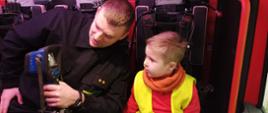 strażak pokazujący chłopcu sprzęt w kabinie wozu bojowego