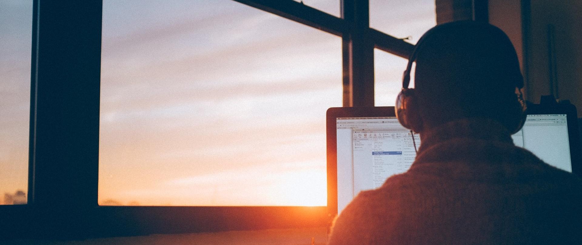 Człowiek w słuchawkach siedzący przed monitorem