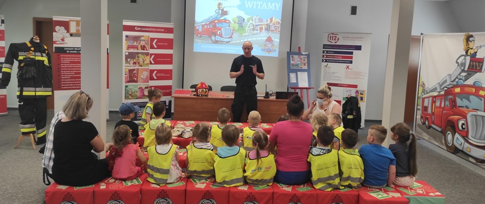 Strażak omawia dzieciom przebieg zajęć w sali edukacyjnej "Ognik"