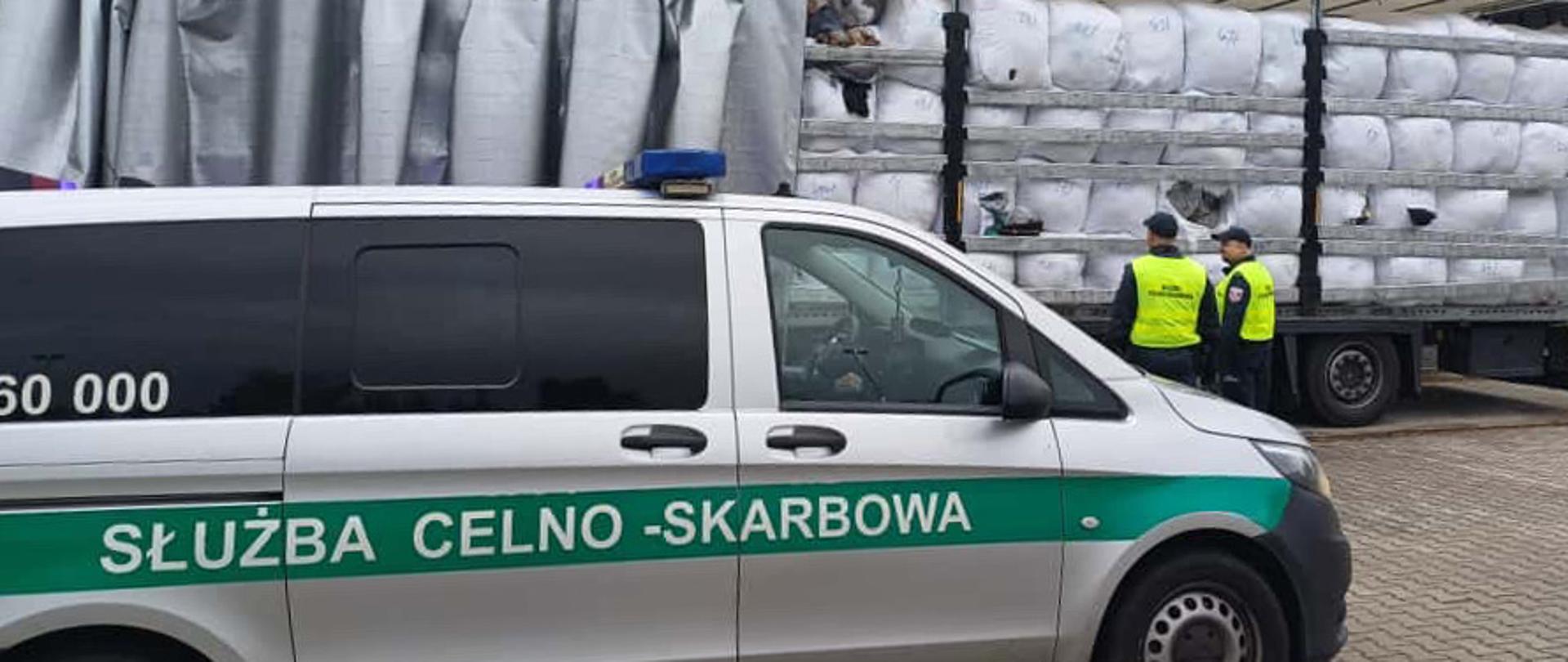 Radiowóz Służby Celno-Skarbowej, funkcjonariusze przy otwartej naczepie z odpadami.