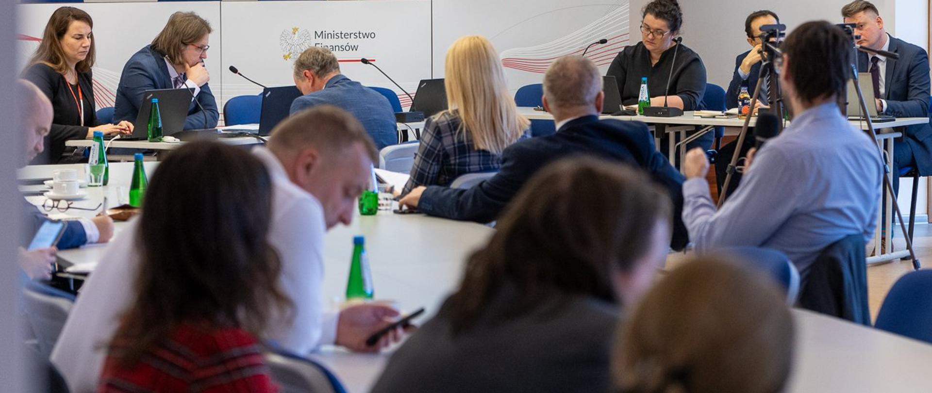 Uczestnicy spotkania przy stołach w dużej sali konferencyjnej. 