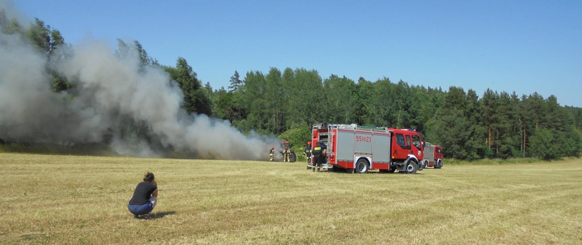 Poglądowe zdjęcie działań na polach. Zdjęcie z działań ratowniczo-gaśniczych w miejscowości Lemany. Strażacy gaszą ciągnik rolniczy.