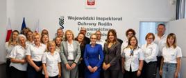 grupa osób stoi pozując do zdjęcia, większość ma białe koszule
