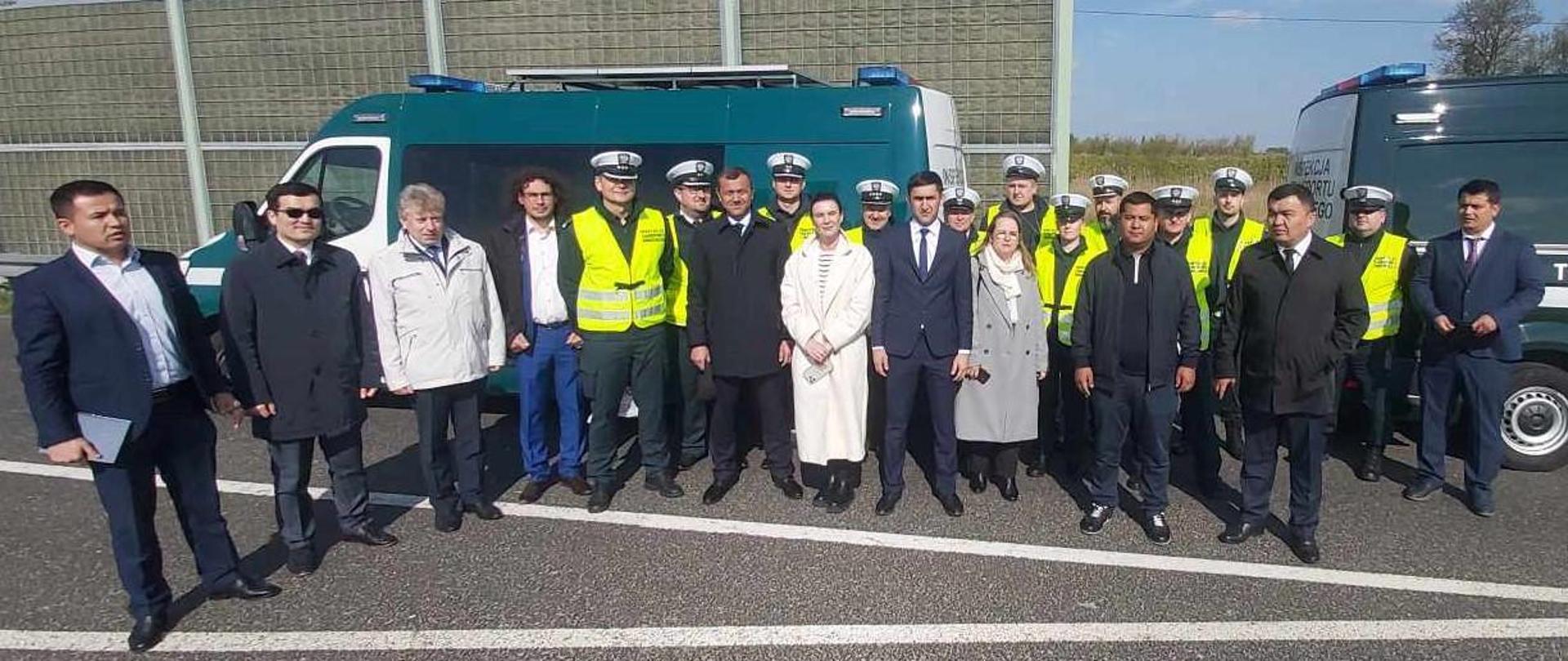 Grupa kilkudziesięciu osób stojących przez radiowozem