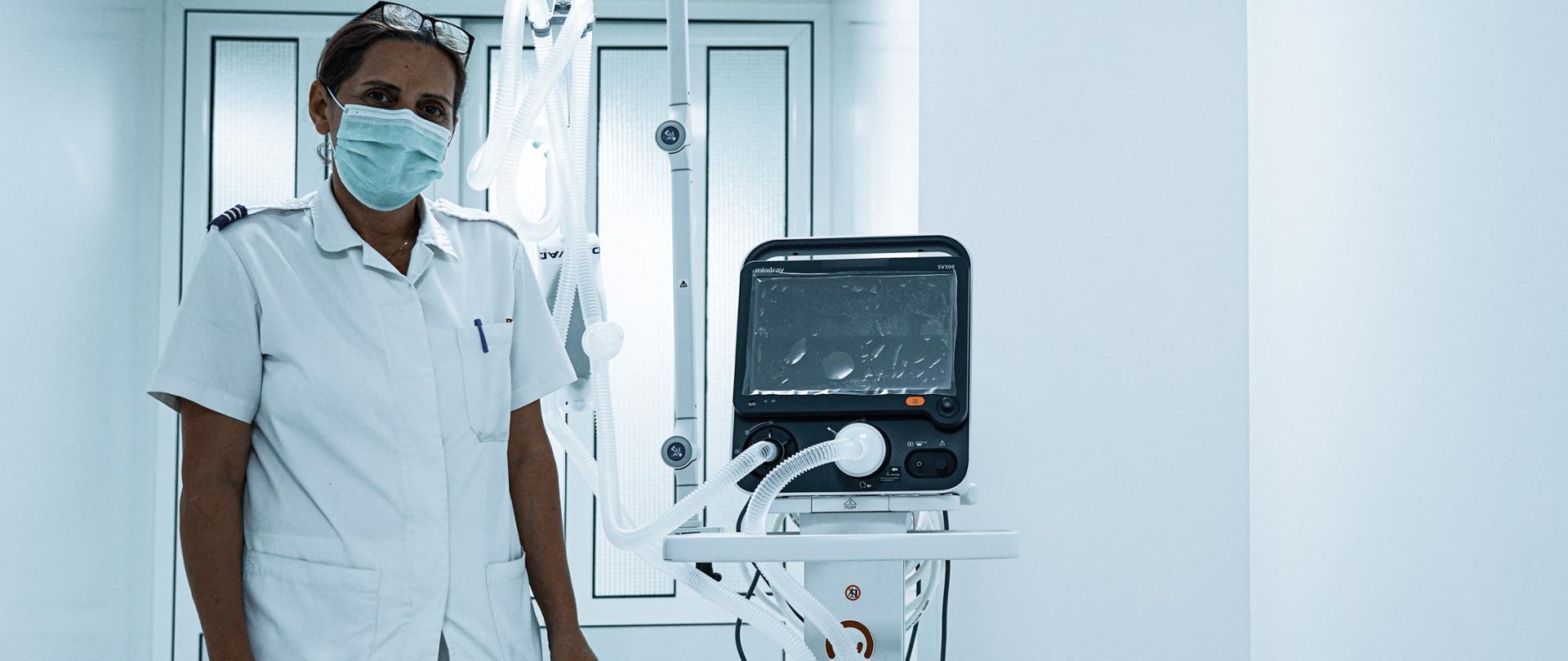 pracownik medyczny stoi obok respiratora oznakowanego naklejką Polish Aid