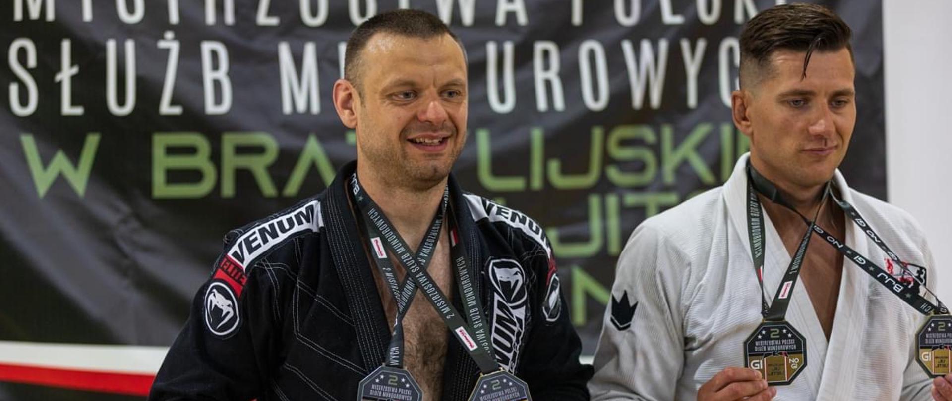 Dwóch strażaków w strojach sportowych z medalami mistrzów na szyi