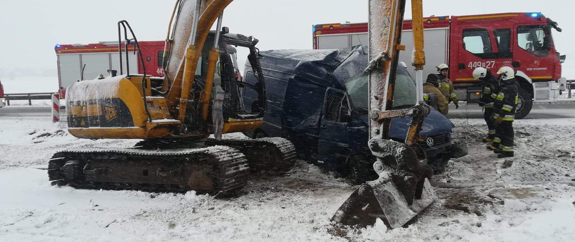 Na zdjęciu widać stojącą koparkę na poboczu oraz uszkodzony bus który w nią uderzył. W tle znajdują się samochody strażackie.