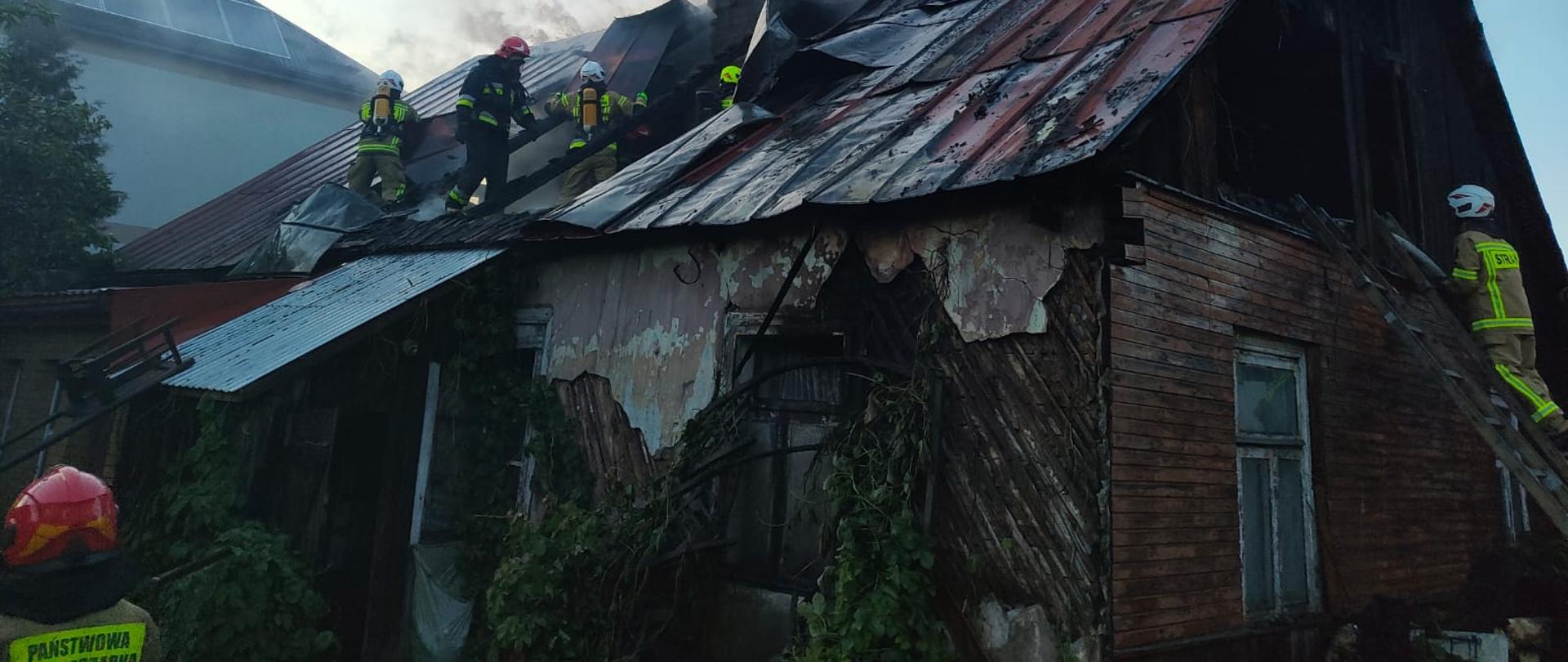 strażacy prowadzą prace rozbiórkowe poszycia dachu