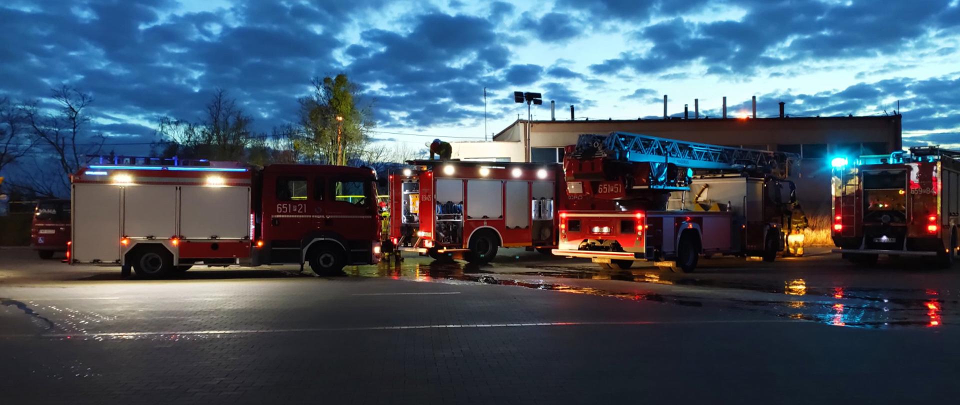 Zdjęcie przedstawia cztery wozy strażackie stojące przed budynkiem