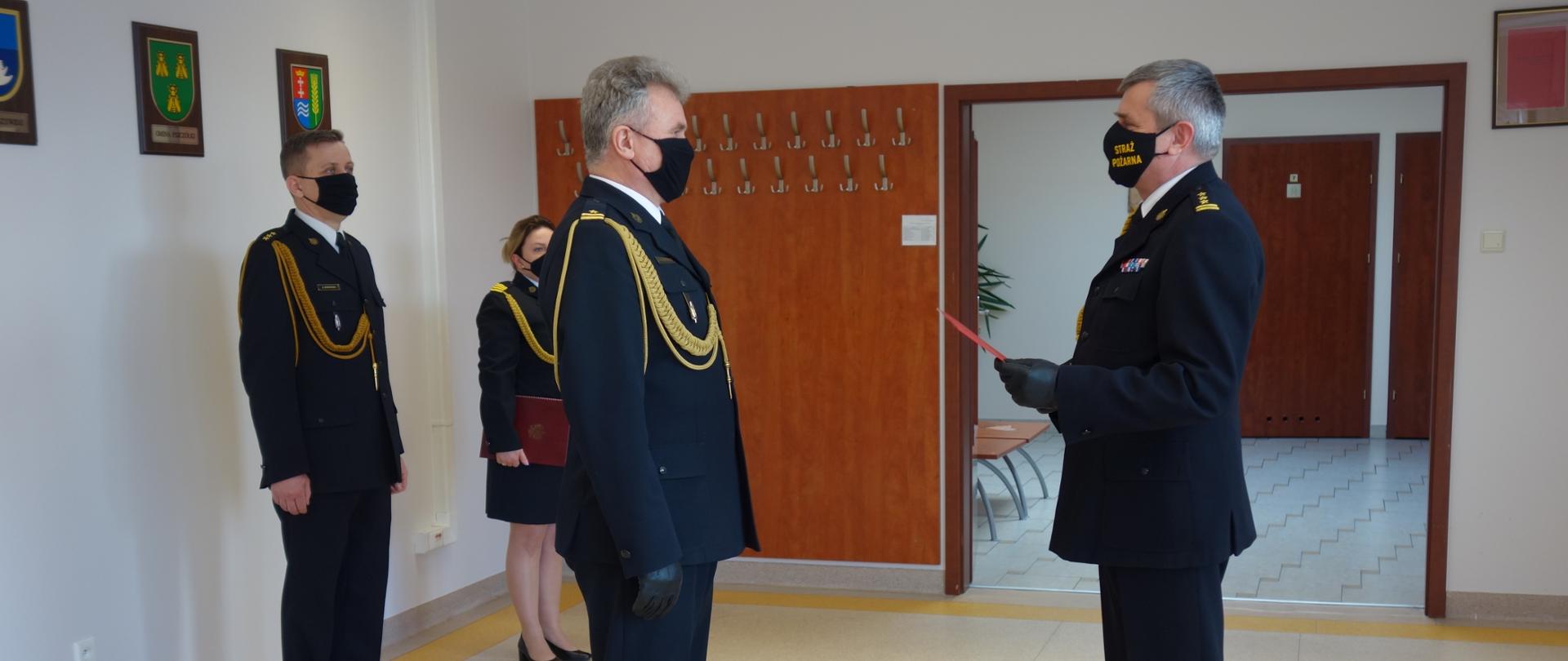 Zdjęcie przedstawia pomorskiego komendanta wojewódzkiego PSP wręczającego akt odwołania ze stanowiska. 