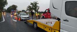 Zderzenie dwóch aut. Droga wojewódzka nr 309 w okolicach Żylic. Na jezdni VW uczestniczący w kolizji, nieoznakowany radiowóz policyjny i dwa wozy straży pożarnej oraz auto-laweta pomocy drogowej. Strażacy przy pomocy mioteł usuwają zanieczyszczenia z jezdni. Widoczny jest policjant i dwie osoby cywilne.