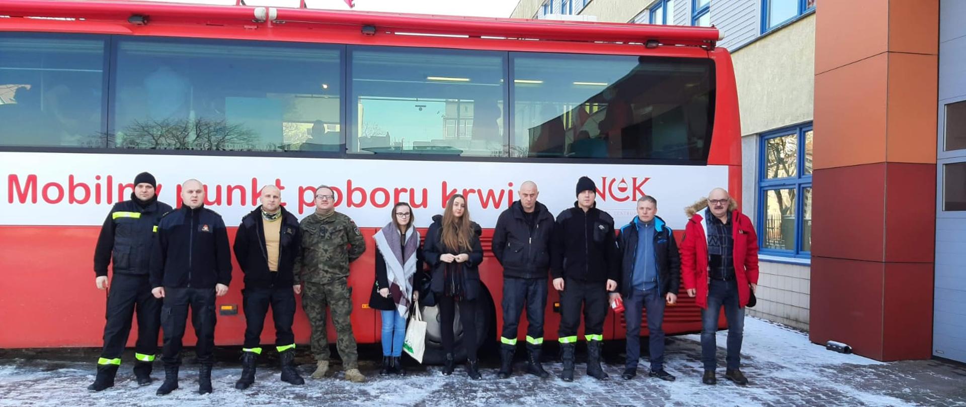 Na tle autobusu - mobilny punkt poboru krwi organizatorzy akcji przed budynkiem Komendy Powiatowej PSP w Stargardzie