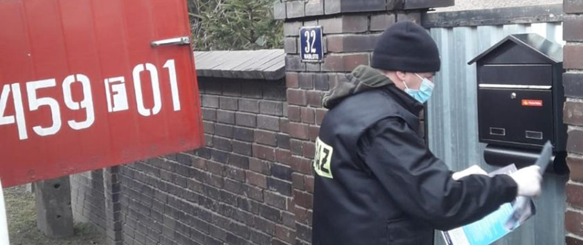 Strażak roznosi ulotki dotyczące szczepienia się przeciw Covid-19. Wrzuca do skrzynki.