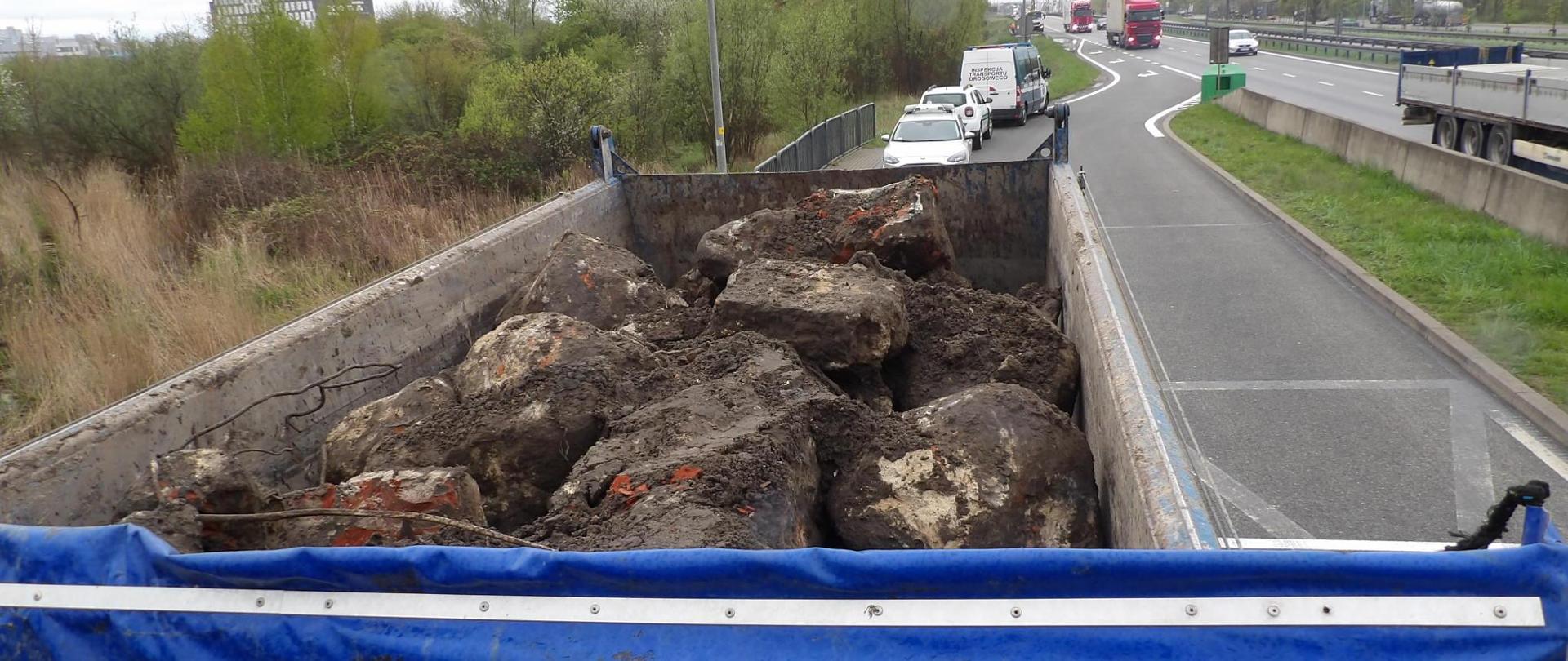 Widok z góry na pojazd ciężarowy transportujący odpady gruzu, w tle oznakowane pojazdy: Inspekcji Ochrony Środowisko oraz Wojewódzkiego Inspektoratu Transportu Drogowego w Gdańsku;