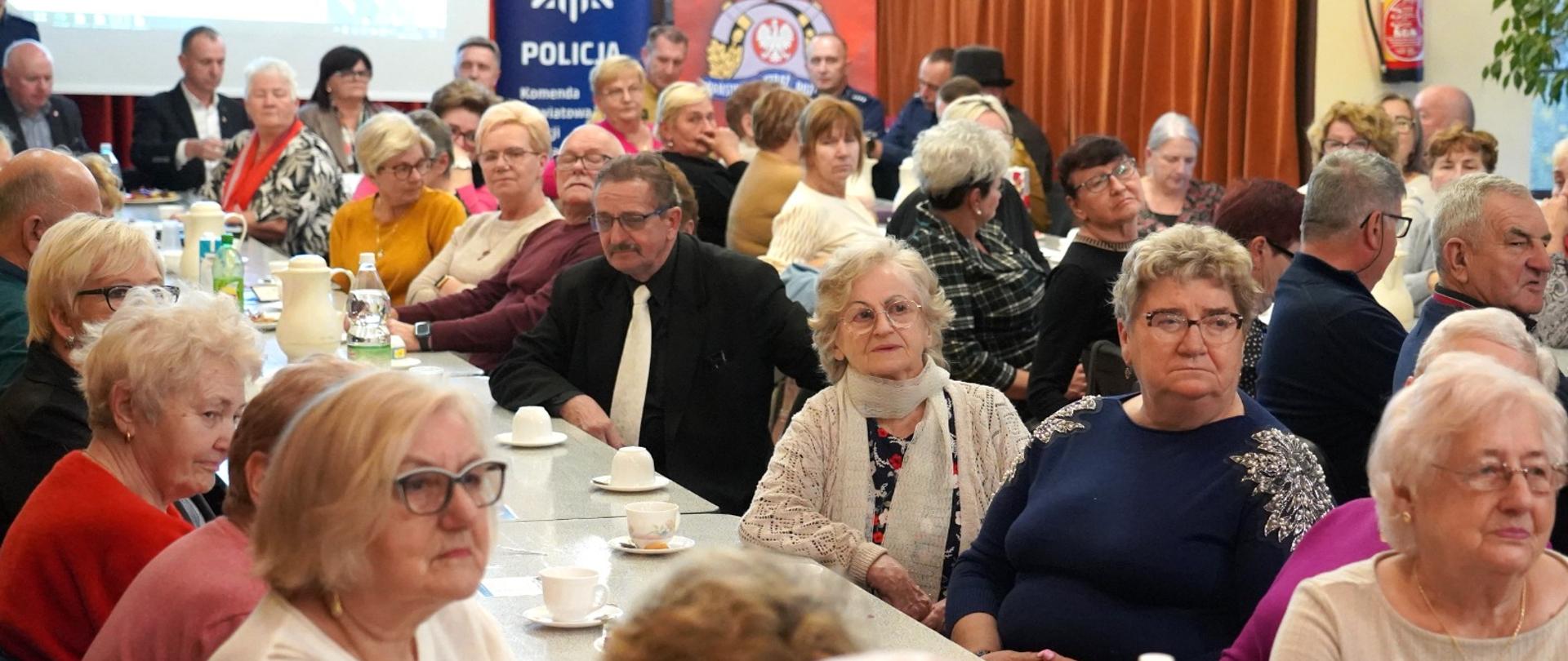 Słuchacze Uniwersytetu Trzeciego Wieku przy stołach