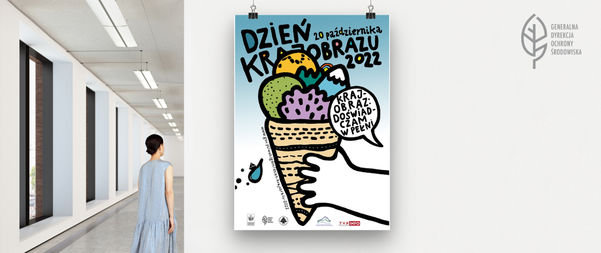Po lewej stronie odwrócona plecami stoi kobieta w jasnoniebieskiej sukience. Po prawej stronie na białej ścianie wisi plakat, na którym znajduje się napis Dzień Krajobrazu 20 października 2022 oraz rysunek przedstawiający rękę trzymającą wafelek z gałkami lodów. 