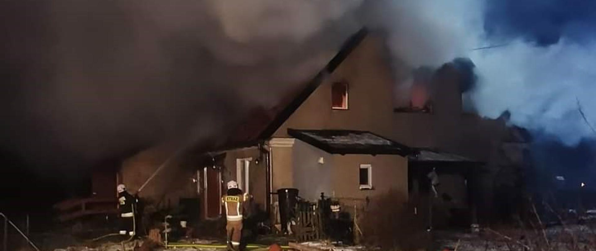 Strażacy gaszą palące się poddasze domu. 