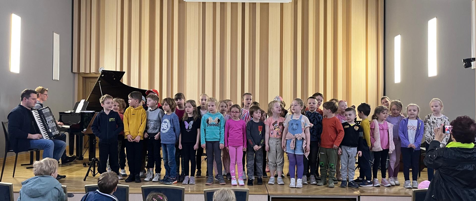 Warsztaty muzyczne w PSM. Galeria zdjęć z warsztatów muzycznych w szkole. Na zdjęciach nauczyciele PSM oraz dzieci ze szkół i przedszkoli.